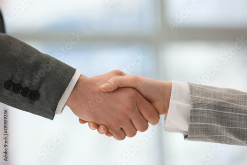 Business man shaking woman's hand in office, closeup