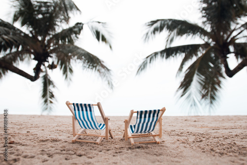 Vacation holidays background wallpaper - two beach lounge chairs under coconut tree on the beach