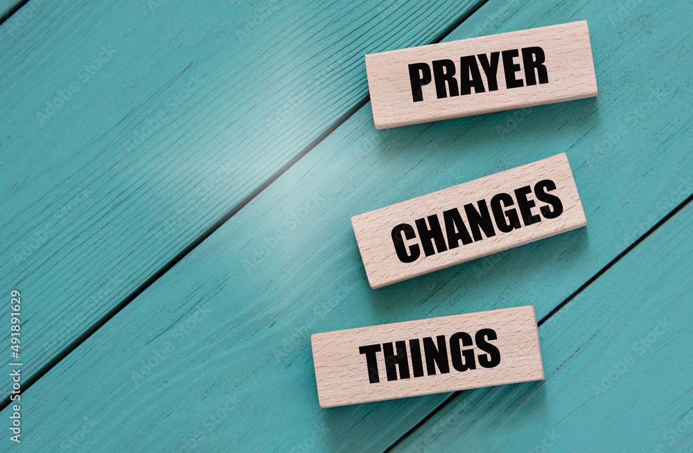 PRAYER CHANGES THINGS - words on wooden blocks on a turquoise background
