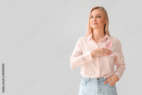 Woman holding pink awareness ribbon on light background. Breast cancer awareness concept