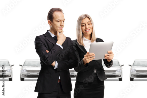 Businessman and businesswoman looking at a tablet in a car showroom