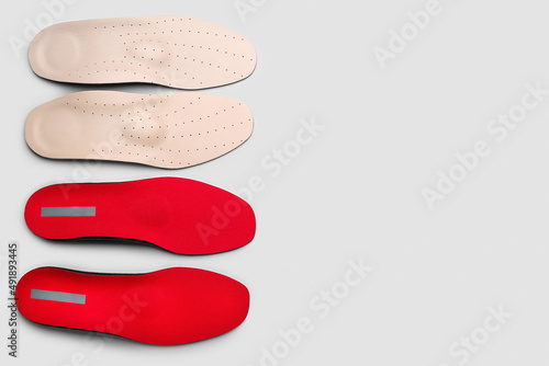 Two pairs of orthopedic insoles on grey background