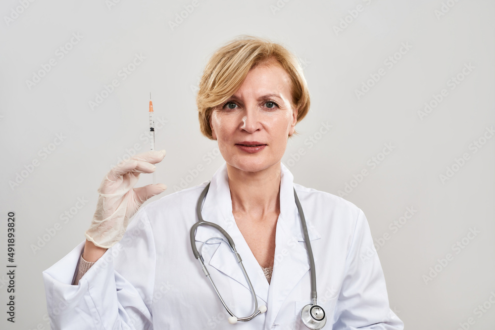 Adult female doctor with syringe looking at camera Adult female doctor with syringe looking at camera
