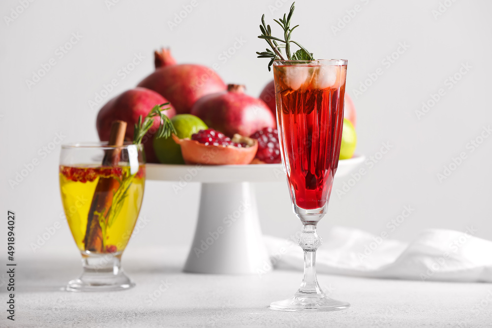 Glasses of tasty pomegranate cocktail on white background