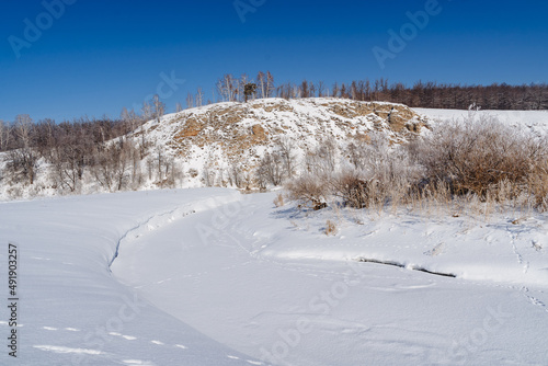 The tranquility of nature in the winter landscape, the silence of the mountains, the frozen river is torn off under a layer of snow.