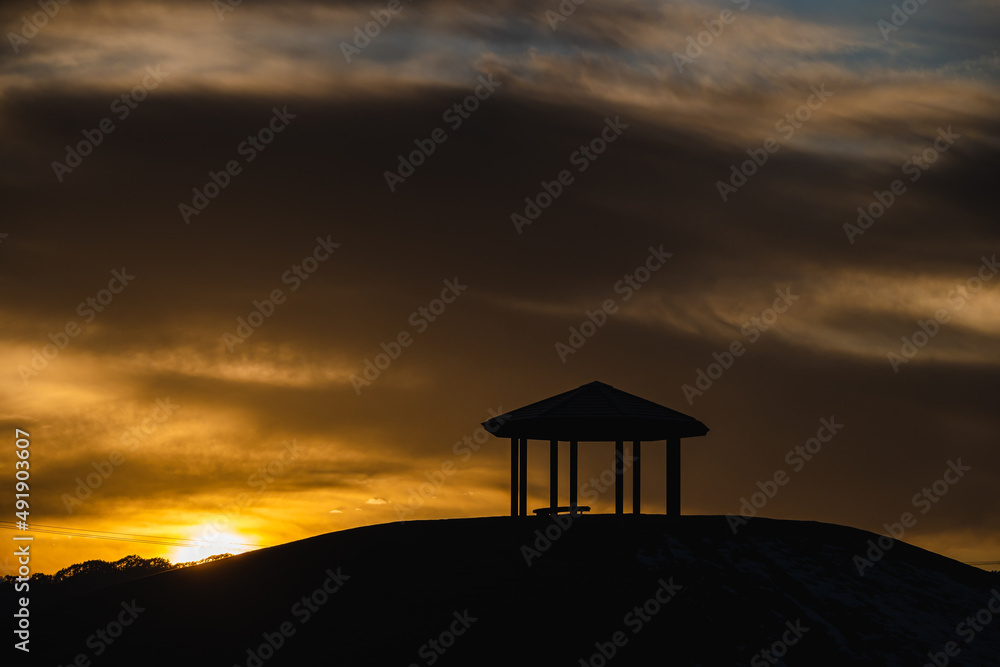夕日にうかぶ丘の上のあずま屋