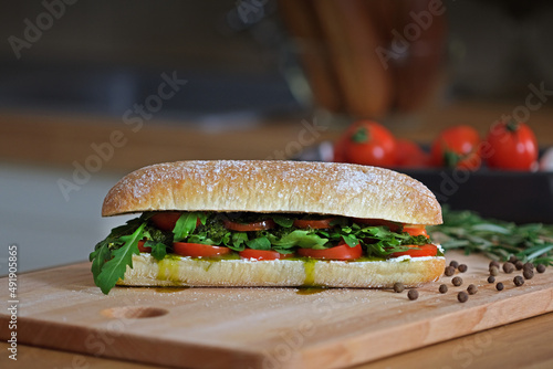 Delicious sandwich with ciabatta bread, tomatoes, mozzarella, basil, cheese, pesto sauce, fresh arugula leaves. Healthy eating. Italian cuisine. Vegetarian cooking concept. Cooking fast food