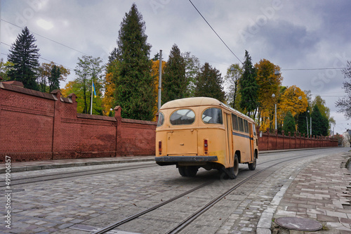 a yellow old bus passing through the city streets, ukraine lviv 