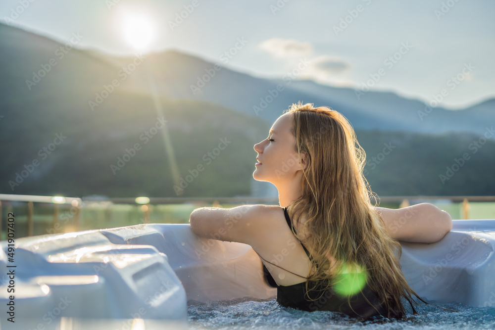Portrait of young carefree happy smiling woman relaxing at hot tub during enjoying happy traveling moment vacation life against the background of green big mountains