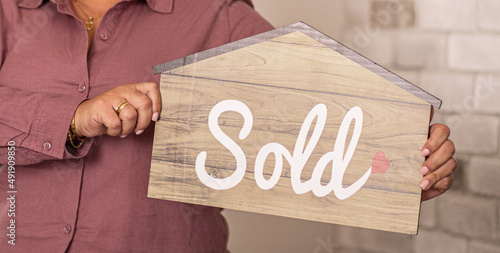 person holding a sold sign in the shape of a house real-estate agent 