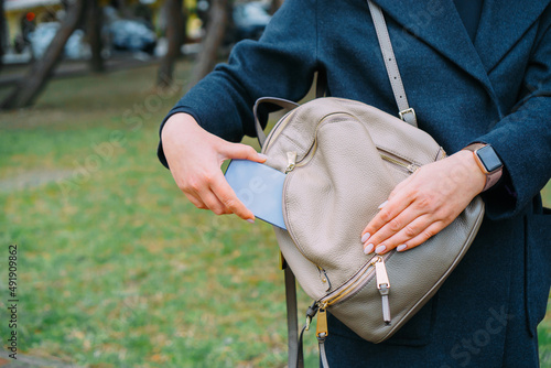 The woman puts the phone in the pocket of her bag.