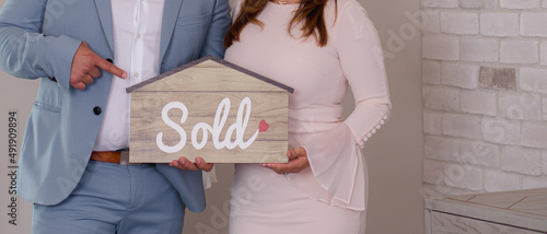 person holding a sold sign in the shape of a house real-estate agent   photo