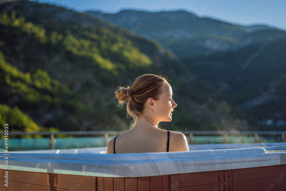 Naklejka premium Portrait of young carefree happy smiling woman relaxing at hot tub during enjoying happy traveling moment vacation life against the background of green big mountains