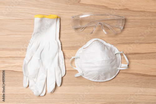 white color protective equipment gloves and mask, goggles on an oak wooden background. Concept on the theme of labor protection. horizontal photo. top view