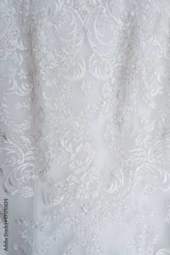 Close-up shiny symbolic flowers pattern on classical white wedding dress