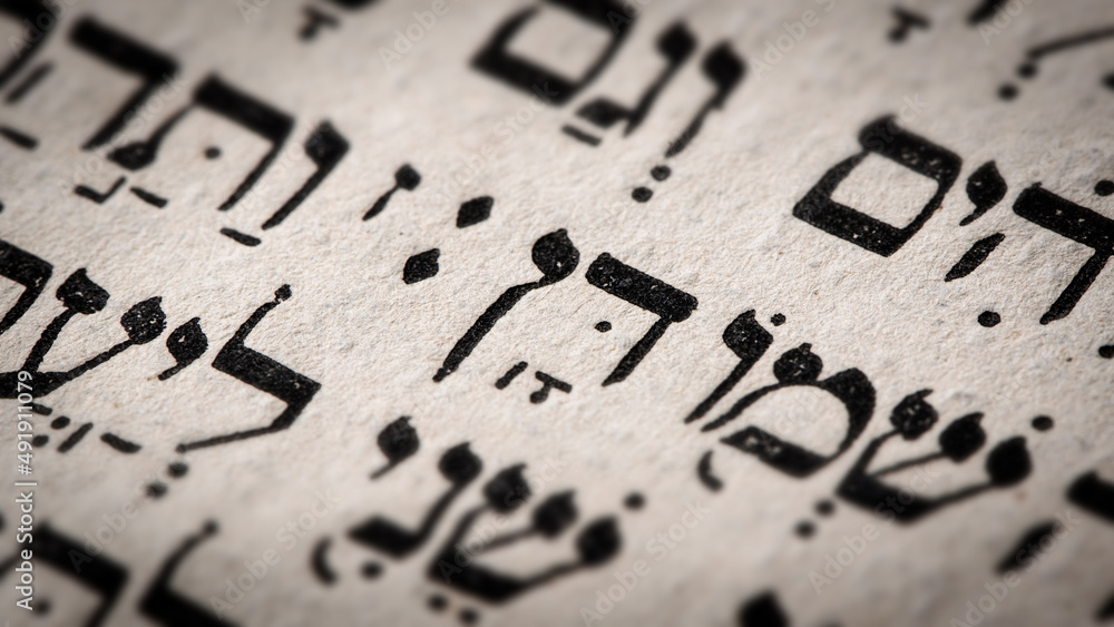 Hebrew word in Torah page. English translation is name Dan, the founder of the Israelite Tribe of Dan. First of the two sons of Jacob and Bilhah. Selective focus. Closeup.