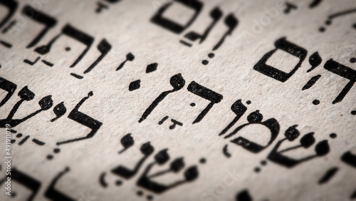 Hebrew word in Torah page. English translation is name Dan, the founder of the Israelite Tribe of Dan. First of the two sons of Jacob and Bilhah. Selective focus. Closeup. photo