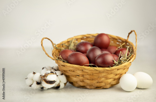 Easter eggs in a wicker basket on white background with cotton brunch