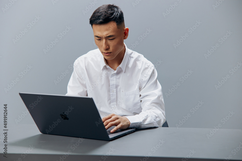 man working on a laptop sitting at a table in the office Lifestyle work man working on a laptop sitting at a table in the office Lifestyle work