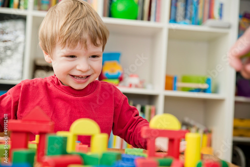 A young builder. kid building city from wooden blocks. Kids Play Room. Development and Construction Concept. Toy to learn stimulates imagination, creativity, hand-eye coordination.