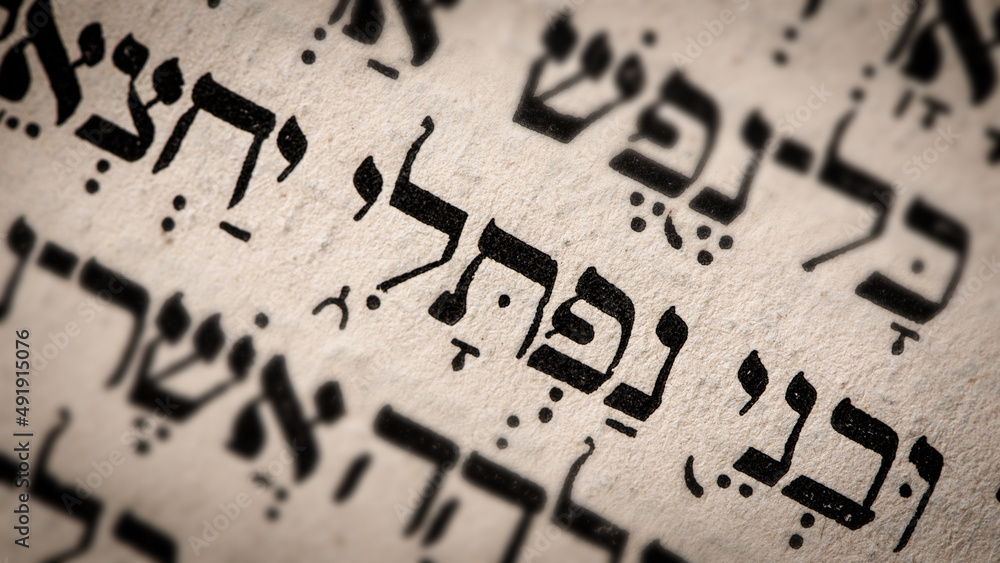 Hebrew word in Torah page. English translation is name Naphtali, the founder of the Israelite Tribe of Naphtali. The last of the two sons of Jacob and Bilhah. Selective focus. Closeup.
