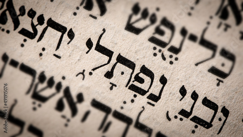Obraz na płótnie Hebrew word in Torah page. English translation is name Naphtali, the founder of the Israelite Tribe of Naphtali. The last of the two sons of Jacob and Bilhah. Selective focus. Closeup. w salonie