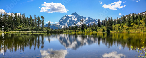Mount Shuksan with reflections in Picture lake in Mount Baker recreation area, Evergreen trees by the lake Washington Pacific Northwest USA.