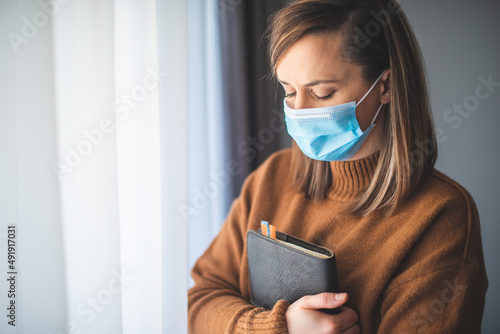 Portrait of a woman with a surgical mask on her face and a bible held tight to her chest