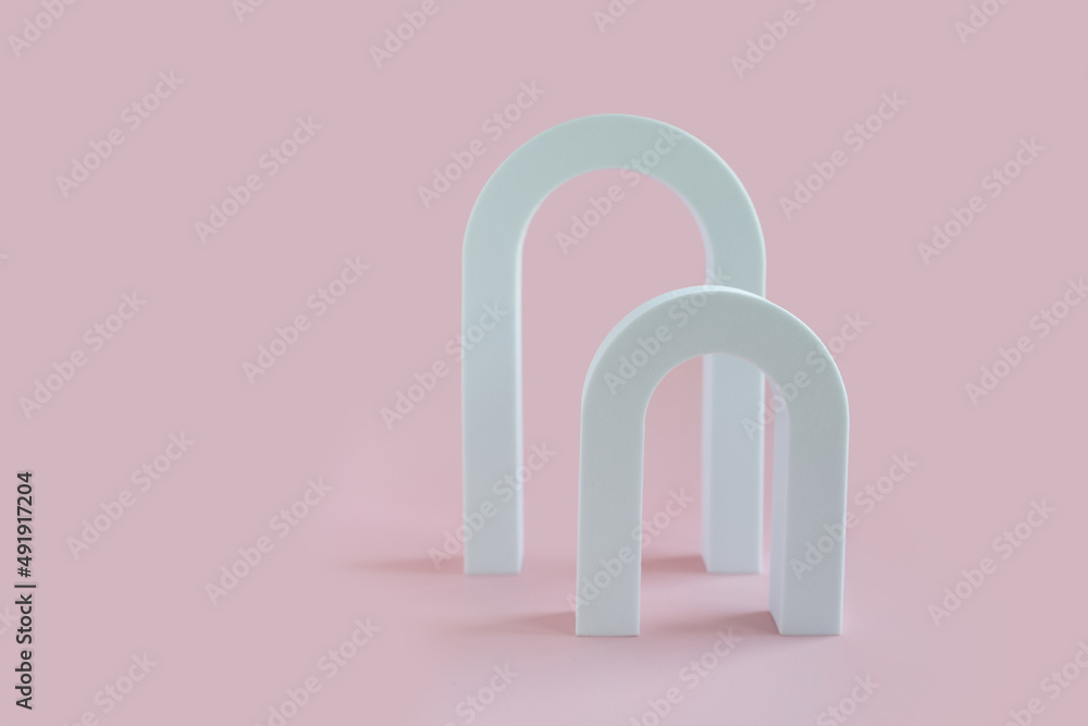 White geometric shapes on a pink bright background with space for text and design. Minimalistic composition of white geometric shapes of arches. Abstract composition for any text. White geometric shapes on a pink bright background with space for text and design. Minimalistic composition of white geometric shapes of arches. Abstract composition for any text.