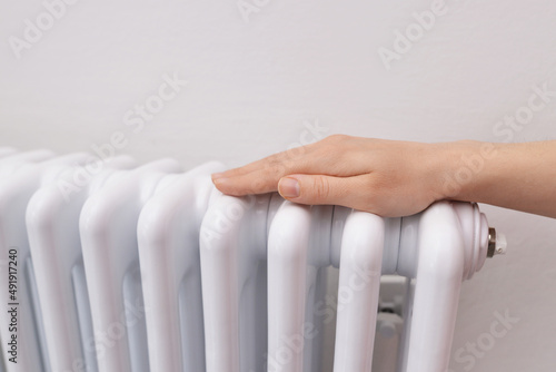 A Female Warms Hands over a Battery, a Heater at Home in a Room. Fingers, palms keeping warm from the radiator, close up. Low room temperature. Winter heating period, season