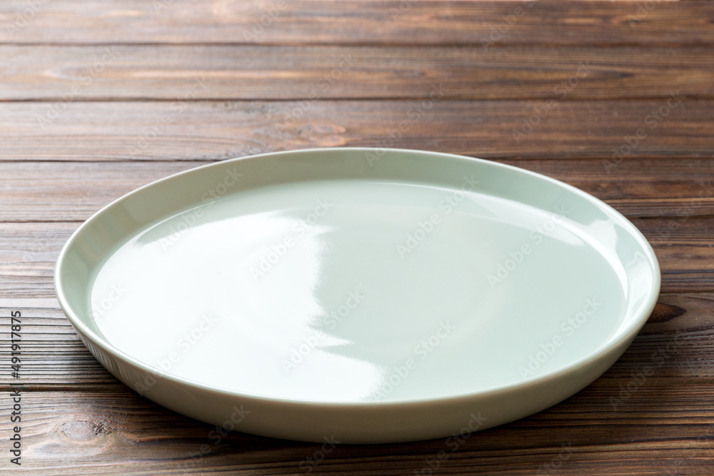 Perspective view of empty blue plate on wooden background. Empty space for your design Perspective view of empty blue plate on wooden background. Empty space for your design