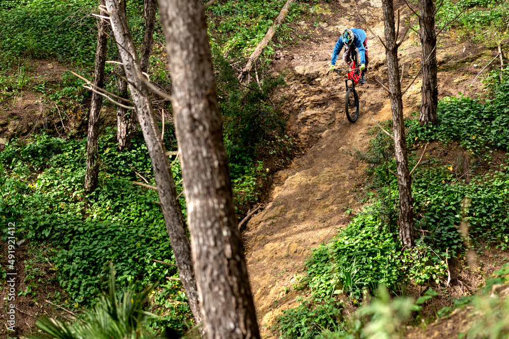 Young cyclist downhill in dangerous trail in the forest Young cyclist downhill in dangerous trail in the forest