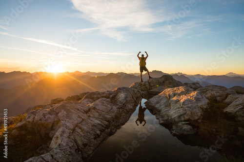 Successful hiker reaches mountain summit at sunset. photo