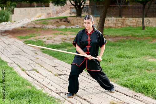 Woman in uniform practicing martial arts with a stick photo