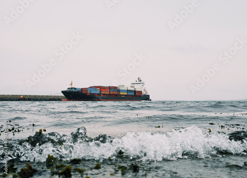 Cargo ship against pier in wavy sea in port photo