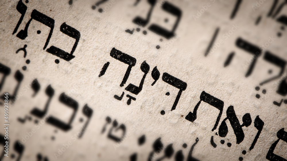 Hebrew word in Torah page. English translation is name Dinah. Daughter of Jacob and Leah. Selective focus. Closeup.