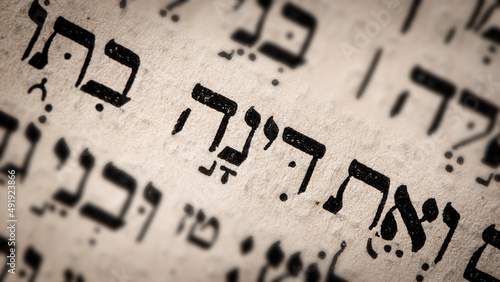 Hebrew word in Torah page. English translation is name Dinah. Daughter of Jacob and Leah. Selective focus. Closeup. photo