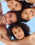Theyre a close young family. A family of four in swimwear smiling against a bright sky.