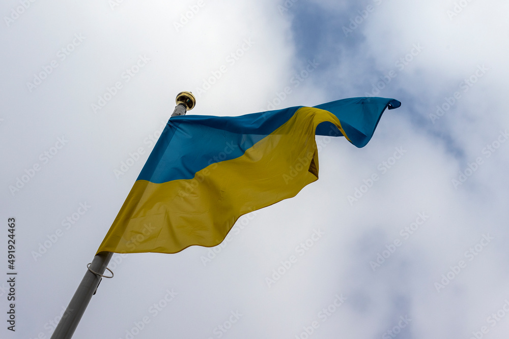 Fototapeta premium Big flag of Ukraine on a high flagpole against a cloudy sky.