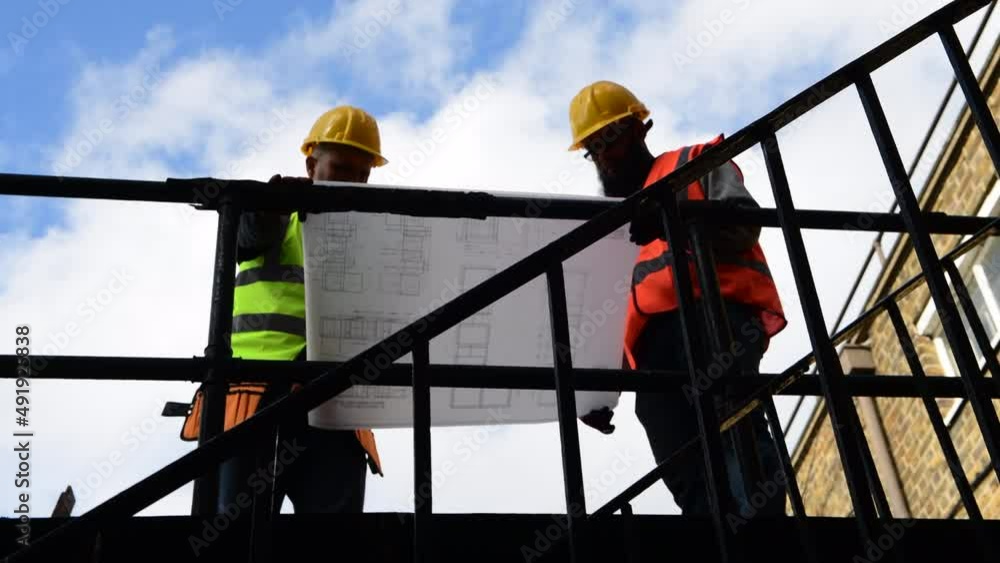 A construction worker and supervisor studying the building plan. A construction worker and supervisor studying the building plan.