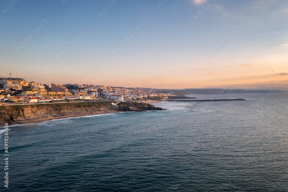 Ericeira drone aerial view on the coast of Portugal with surfers on the sea at sunset