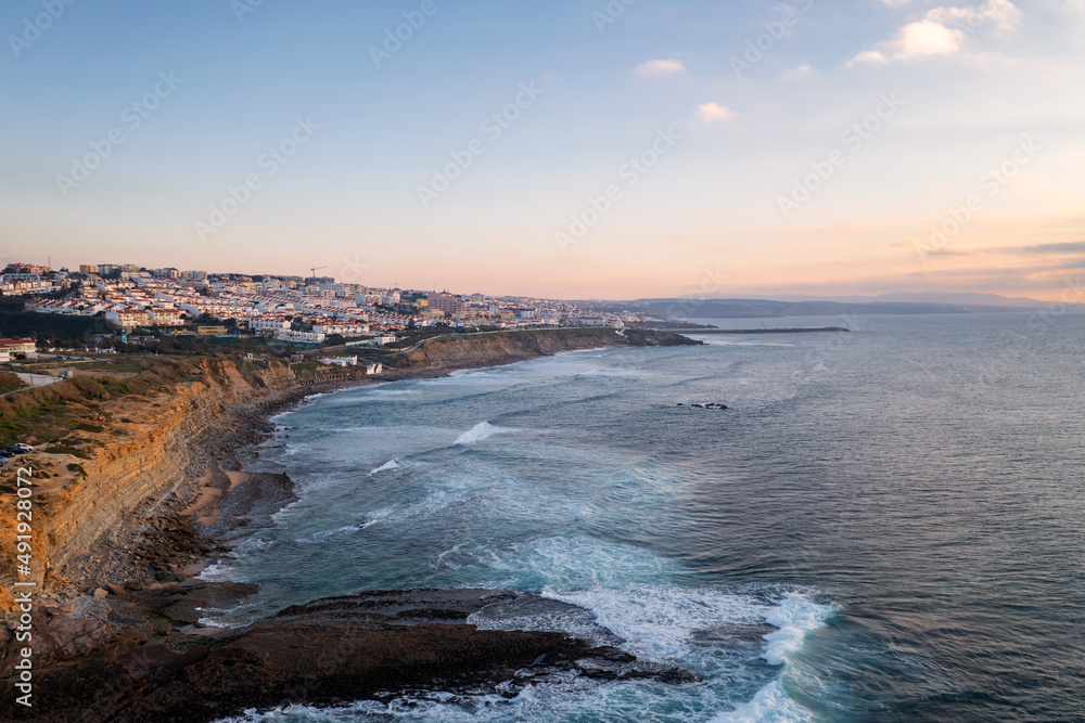 Fototapeta premium Ericeira drone aerial view on the coast of Portugal with surfers on the sea at sunset