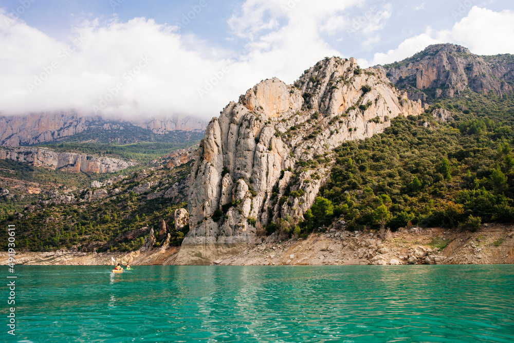 Landscape of a mountain lake with two kayakers doing a route. Landscape of a mountain lake with two kayakers doing a route.