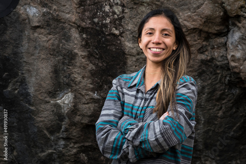 A female rock climbing smiles in front of a boulder photo