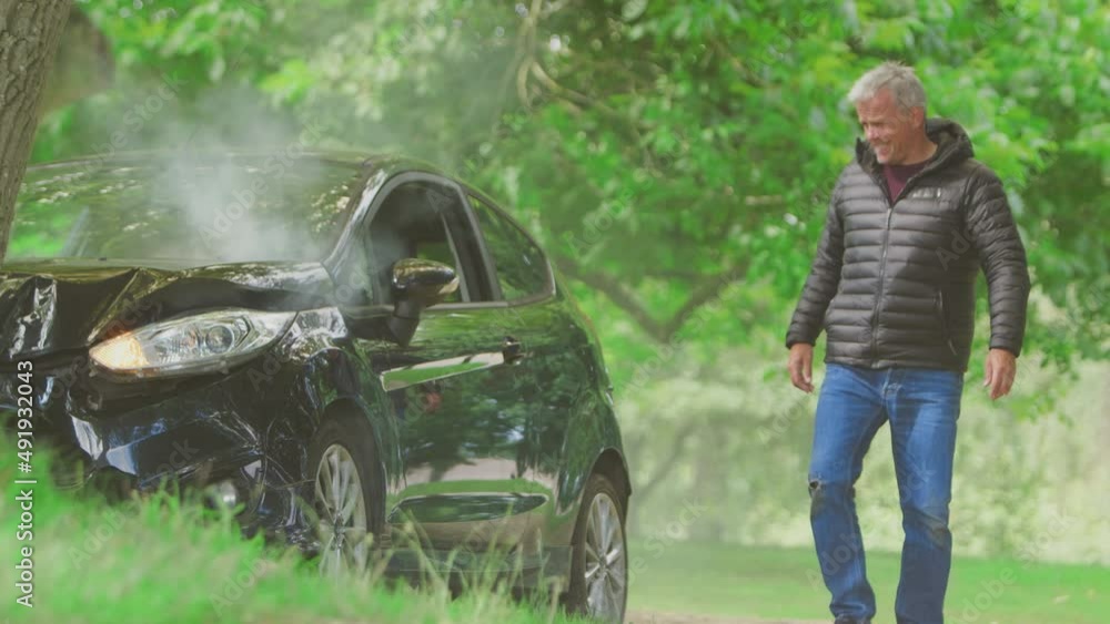 Mature man getting out of smoking car and taking photo of damage on mobile phone for insurance claim - shot in slow motion Mature man getting out of smoking car and taking photo of damage on mobile phone for insurance claim - shot in slow motion