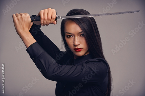 The way of the ninja. Studio portrait of a beautiful young woman in a martial arts outfit wielding a samurai sword.