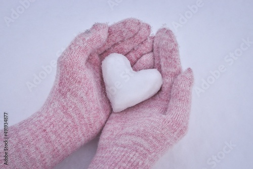 Winter conceptual photo. Heart of snow in female hands.