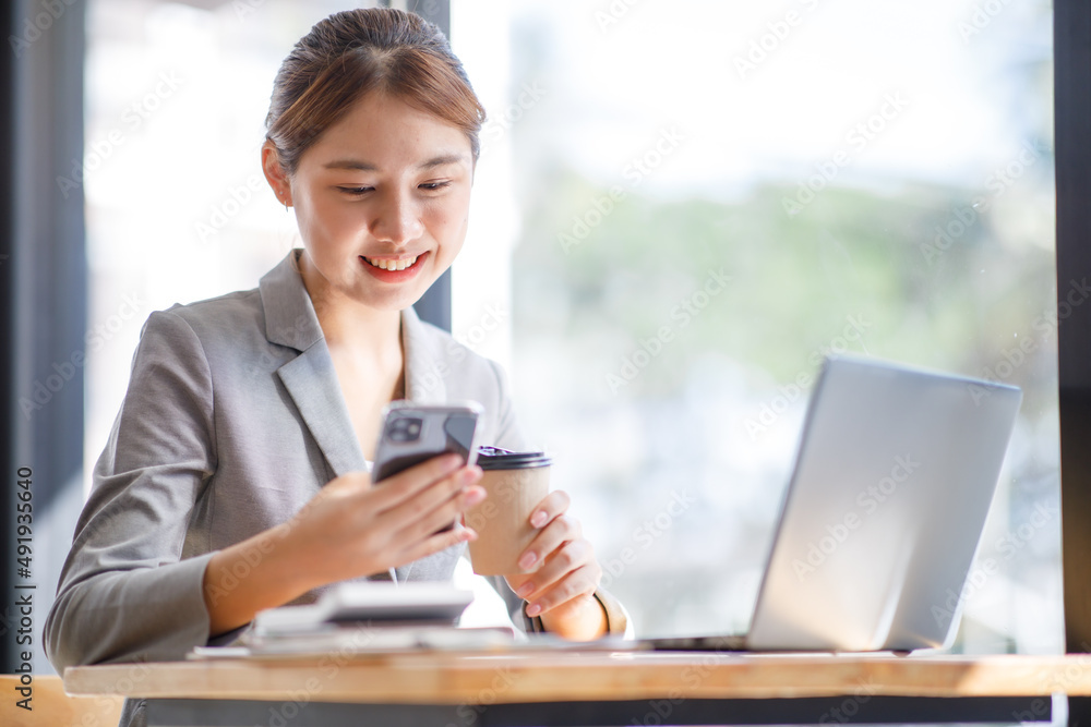 Portrait of an attractive Asian young woman holding her smartphone while working in a coffee shop. Portrait of an attractive Asian young woman holding her smartphone while working in a coffee shop.