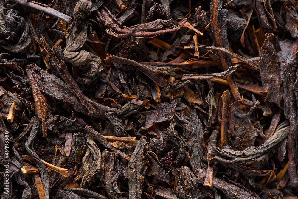 Black large-leaf tea as abstract background. Texture of dry black tea leaves. Dark background Black large-leaf tea as abstract background. Texture of dry black tea leaves. Dark background