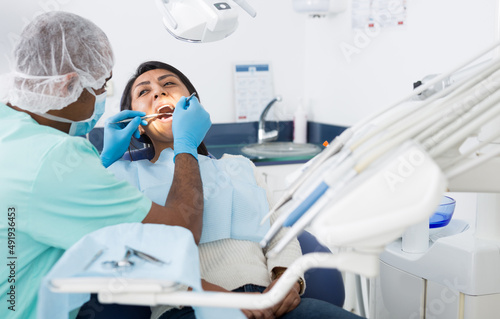 Male dentist treating female patient in dental office